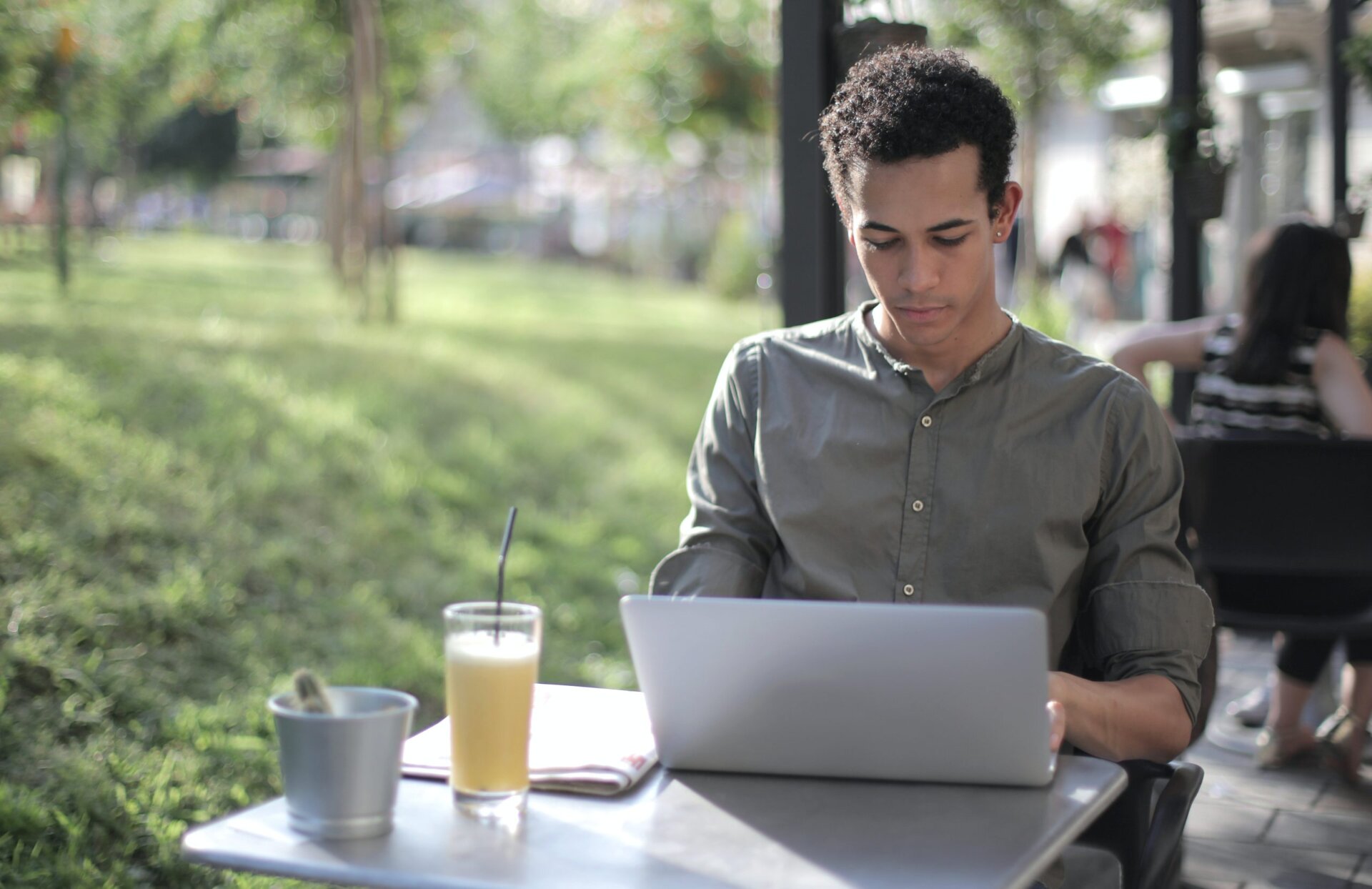 man using laptop outdoors with yummy drink